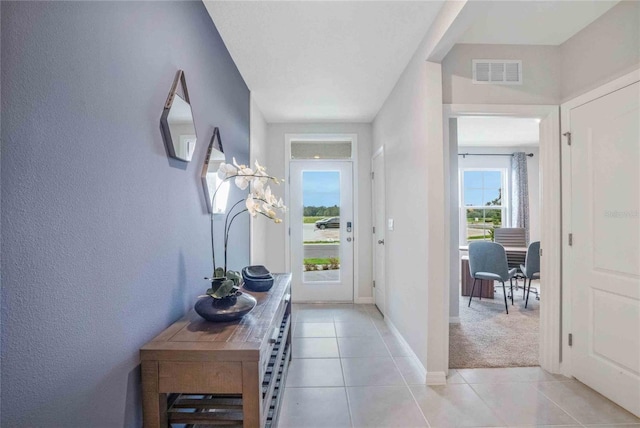 doorway featuring light tile patterned floors and baseboards