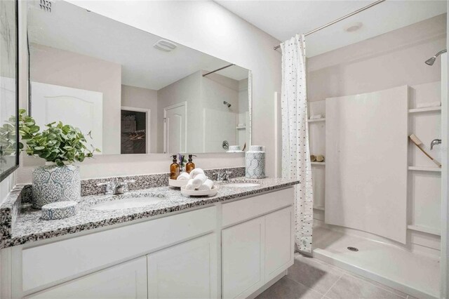 full bath featuring a shower, double vanity, and tile patterned floors