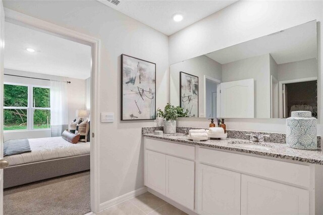 ensuite bathroom with double vanity, baseboards, tile patterned flooring, and recessed lighting