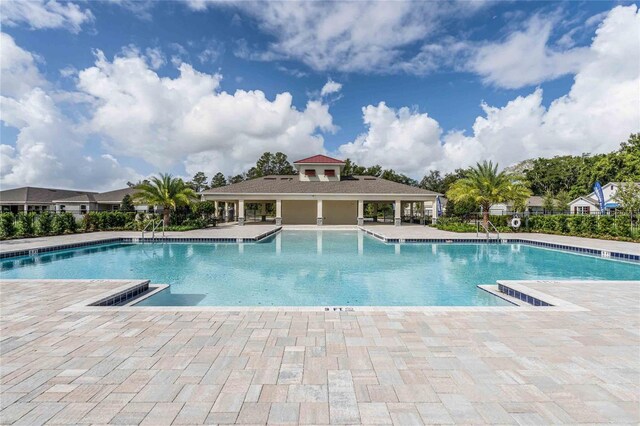 community pool featuring fence and a patio