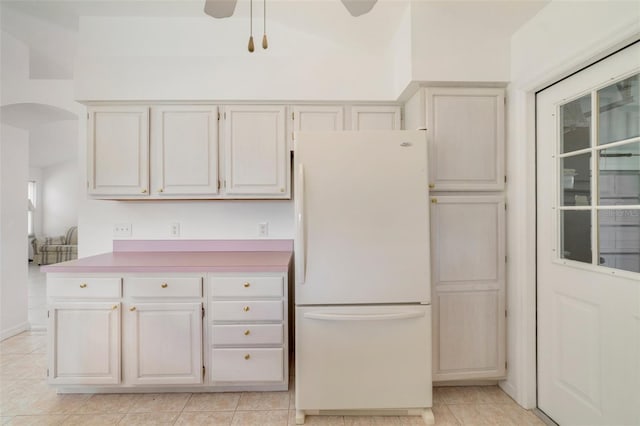 1243 Tangerine Cir, Lady Lake, FL 32159 - kitchen with freestanding refrigerator, light tile patterned floors, a ceiling fan, arched walkways, and light countertops