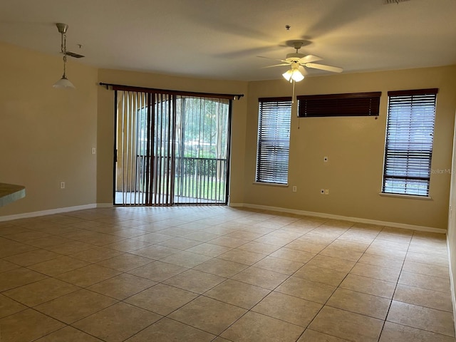 empty room with light tile patterned flooring, a ceiling fan, and baseboards