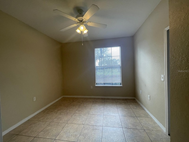 unfurnished room with light tile patterned floors, ceiling fan, and baseboards