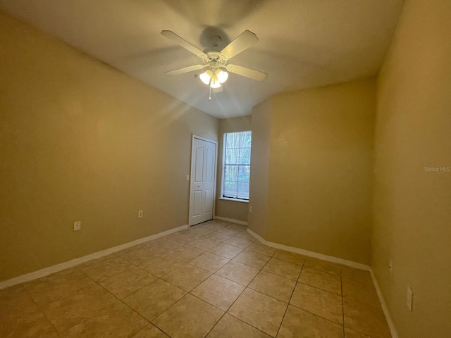 spare room with light tile patterned floors, ceiling fan, and baseboards