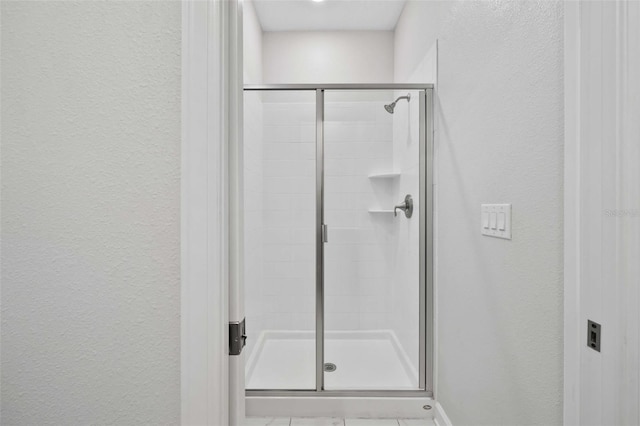1128 Challenge Dr, Davenport, FL 33896 - bathroom with a textured wall, a stall shower, and baseboards