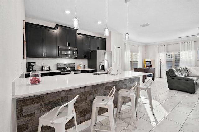1128 Challenge Dr, Davenport, FL 33896 - kitchen featuring stainless steel appliances, dark cabinetry, open floor plan, a breakfast bar area, and light countertops