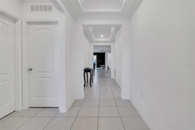 corridor with crown molding, light tile patterned flooring, baseboards, and a raised ceiling