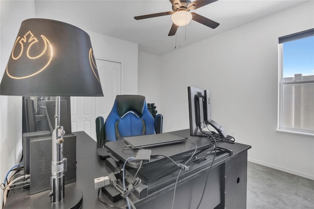 carpeted office space featuring ceiling fan and baseboards