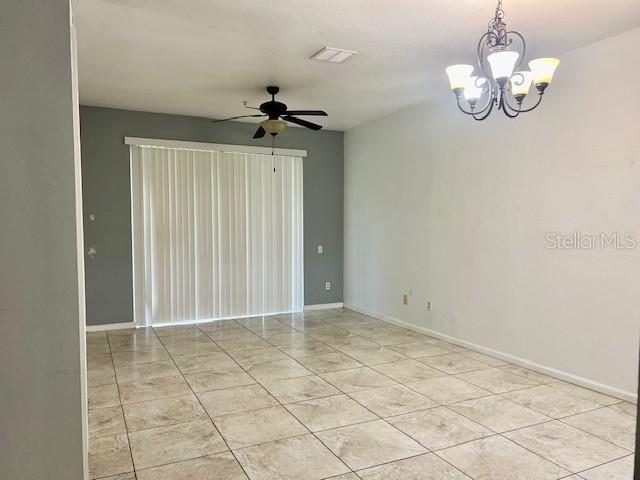 spare room featuring ceiling fan, a chandelier, baseboards, and light tile patterned floors
