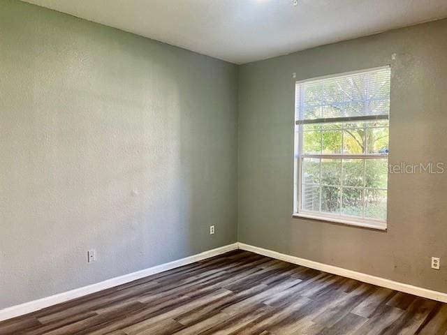 spare room with dark wood finished floors and baseboards