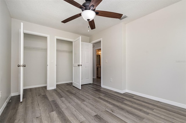 175 Cliff St, Deland, FL 32720 - unfurnished bedroom featuring two closets, wood finished floors, baseboards, and a textured ceiling