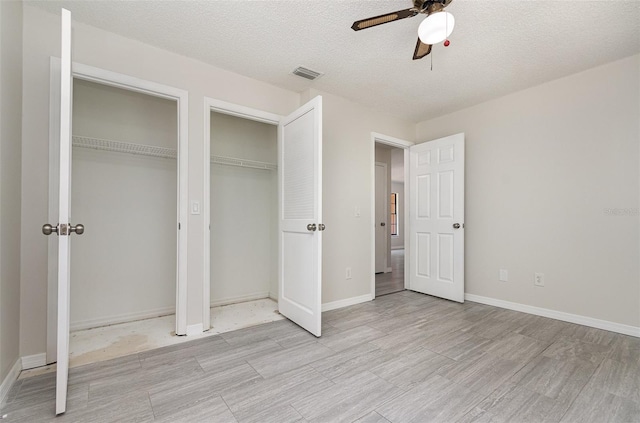 175 Cliff St, Deland, FL 32720 - unfurnished bedroom featuring two closets, light wood-style flooring, ceiling fan, baseboards, and a textured ceiling