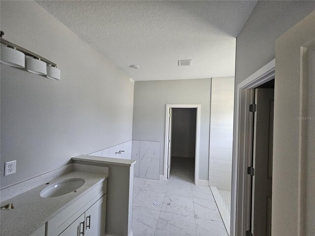 141 W G H Washington St, Apopka, FL 32703 - bathroom with marble look tiles, a textured ceiling, vanity, and a tile shower