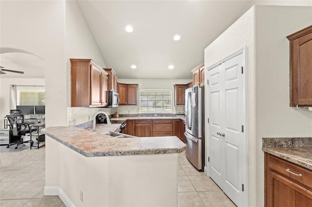 kitchen with stainless steel appliances, a sink, light tile patterned floors, a peninsula, and vaulted ceiling