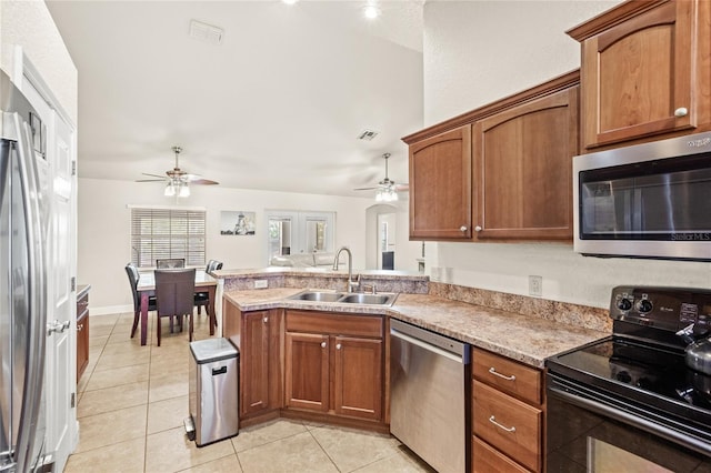 kitchen with stainless steel appliances, a sink, ceiling fan, light tile patterned floors, and a peninsula