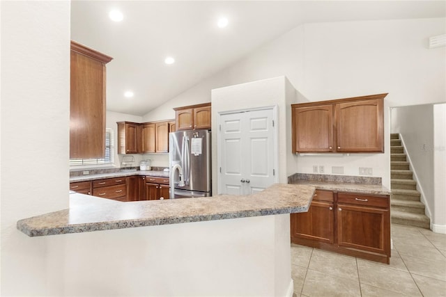 kitchen featuring freestanding refrigerator, vaulted ceiling, a peninsula, light countertops, and light tile patterned floors
