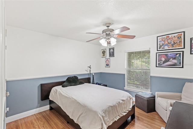 bedroom featuring wood finished floors, a ceiling fan, and baseboards