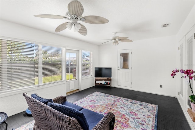 living area featuring ceiling fan and dark colored carpet