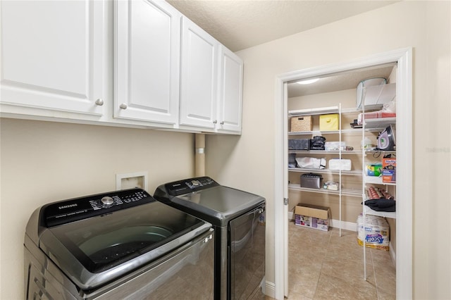 washroom with cabinet space, washer and dryer, and light tile patterned floors
