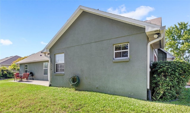 rear view of house with a patio, a lawn, and stucco siding