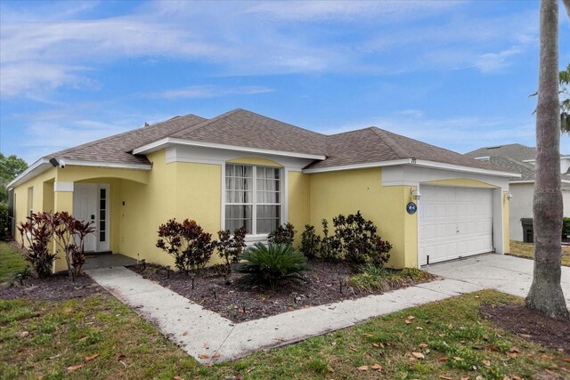 217 Holborn Loop, Davenport, FL 33897 - view of front of property featuring roof with shingles, a garage, stucco siding, and driveway