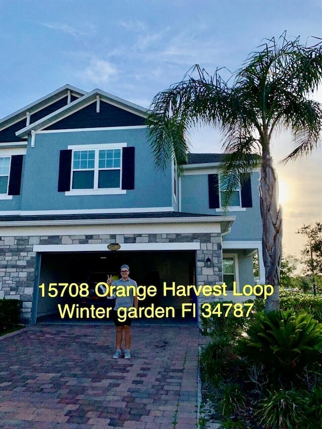 15708 Orange Harvest Loop, Winter Garden, FL 34787 - view of front facade with stucco siding, stone siding, driveway, and a garage