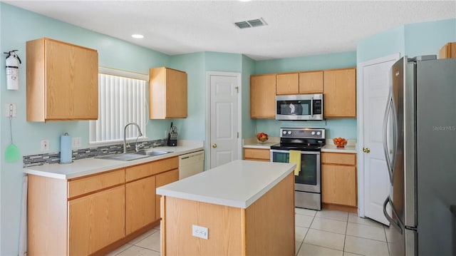 11257 Dacre Ln, Orlando, FL 32824 - kitchen with stainless steel appliances, a sink, a kitchen island, light brown cabinetry, and light tile patterned floors