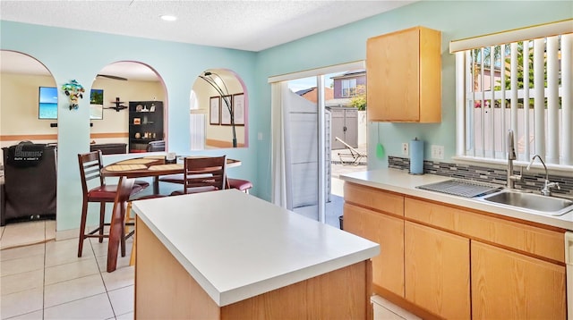 11257 Dacre Ln, Orlando, FL 32824 - kitchen featuring a sink, light brown cabinetry, light countertops, a textured ceiling, and backsplash