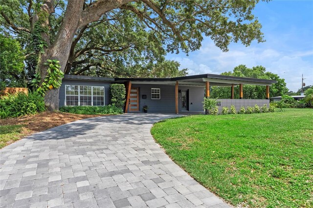 1401 Canberra Ave, Orlando, FL 32806 - mid-century inspired home featuring decorative driveway, a front yard, and an attached carport