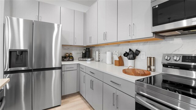 733 Longboat Dr, Davenport, FL 33896 - kitchen featuring appliances with stainless steel finishes, light countertops, tasteful backsplash, gray cabinets, and light wood-type flooring