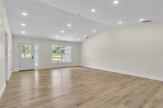 empty room with light wood finished floors, recessed lighting, baseboards, and vaulted ceiling