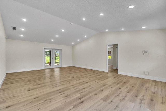 empty room with lofted ceiling, baseboards, light wood finished floors, recessed lighting, and french doors