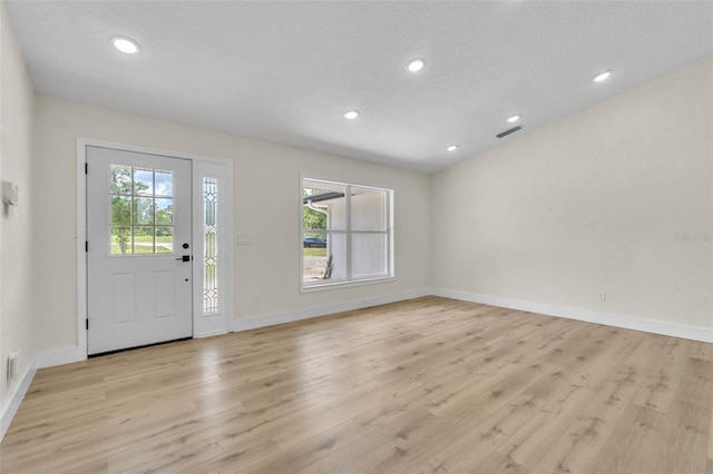 entryway featuring light wood-style floors, baseboards, recessed lighting, and a textured ceiling