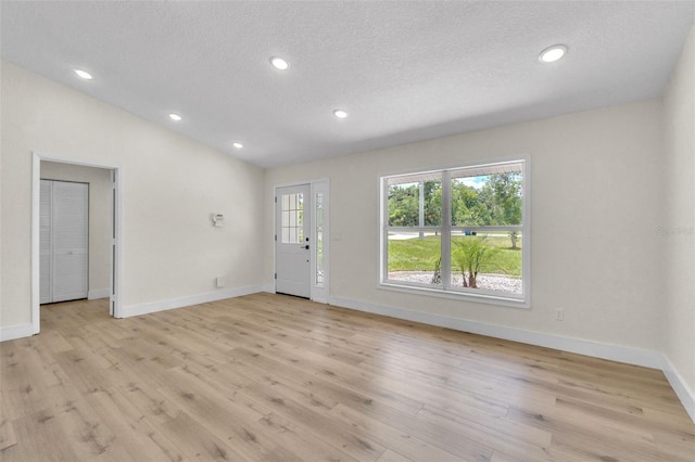 entryway with baseboards, light wood-type flooring, a textured ceiling, recessed lighting, and lofted ceiling