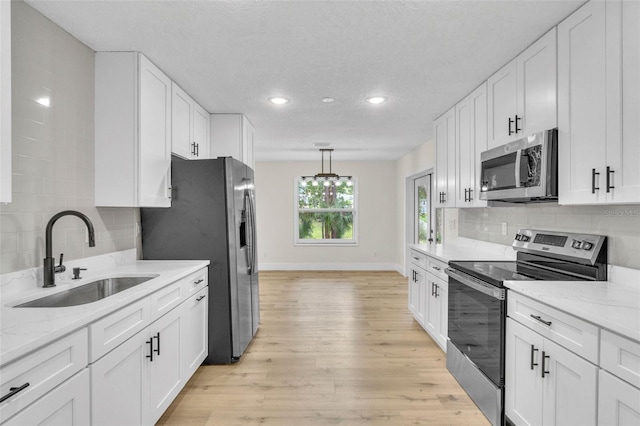 kitchen with stainless steel appliances, a sink, recessed lighting, white cabinets, and backsplash