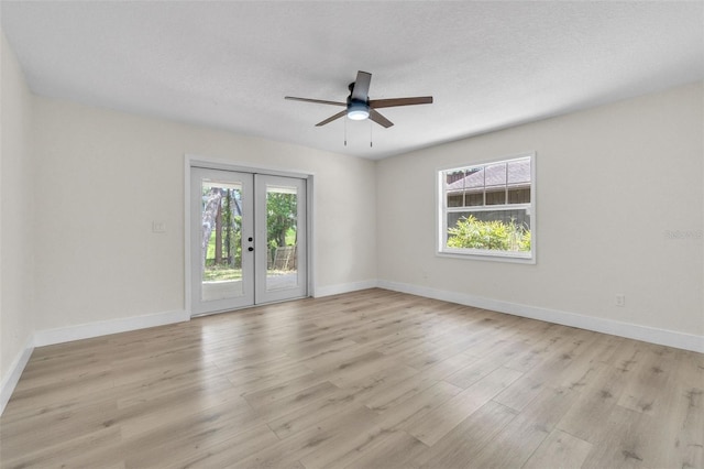 empty room with french doors, light wood-style flooring, ceiling fan, and baseboards