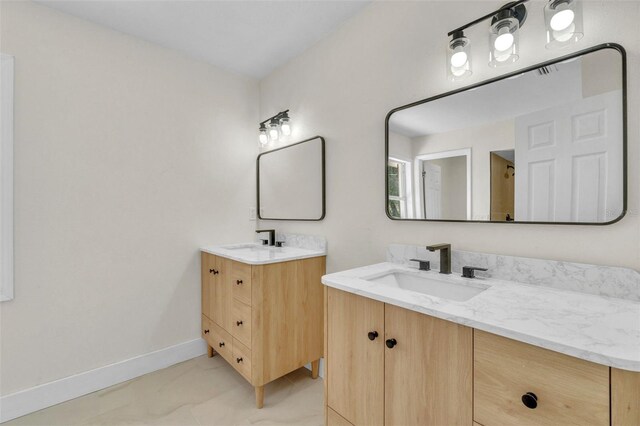full bathroom with two vanities and baseboards