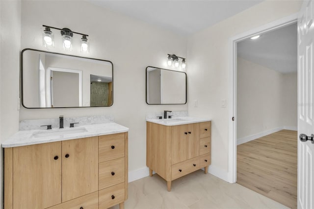 bathroom with baseboards and two vanities