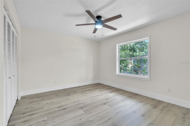 unfurnished bedroom with wood finished floors, baseboards, a closet, and a ceiling fan