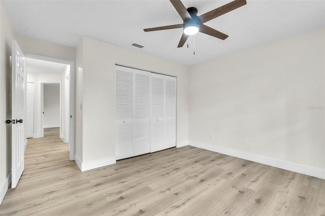 unfurnished bedroom featuring light wood-type flooring, a closet, baseboards, and ceiling fan