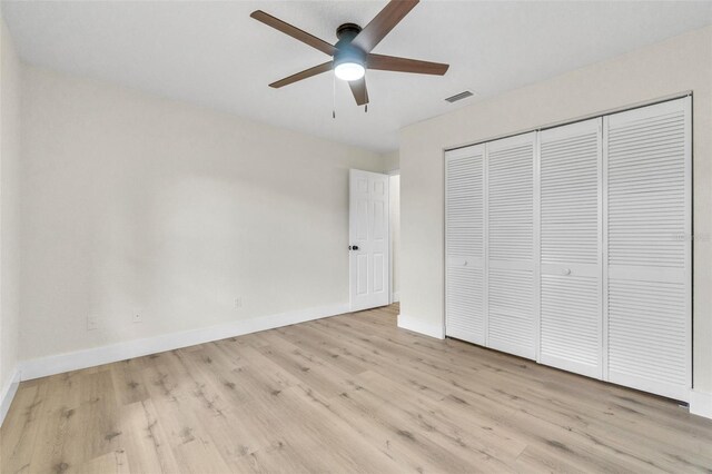 unfurnished bedroom featuring wood finished floors, baseboards, a closet, and a ceiling fan