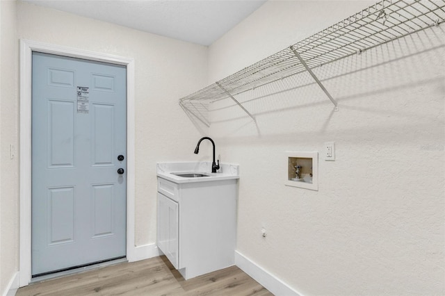 laundry room featuring hookup for a washing machine, light wood-style flooring, baseboards, and cabinet space