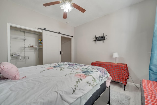 325 Aldridge Ln, Davenport, FL 33897 - bedroom with a barn door, wood finished floors, a closet, baseboards, and a ceiling fan