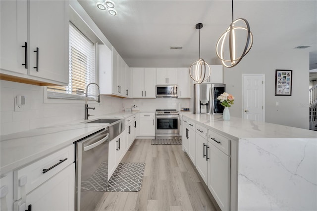 325 Aldridge Ln, Davenport, FL 33897 - kitchen featuring appliances with stainless steel finishes, a sink, light wood-style flooring, a kitchen island, and tasteful backsplash
