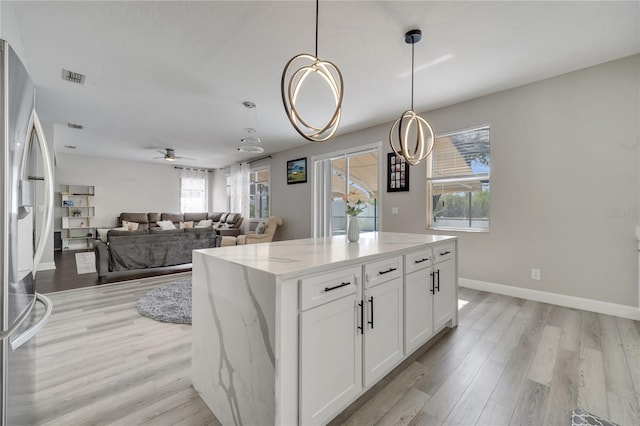 325 Aldridge Ln, Davenport, FL 33897 - kitchen featuring stainless steel fridge with ice dispenser, light wood-type flooring, and light stone counters