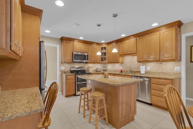 303 S Sweetwater Blvd, Longwood, FL 32779 - kitchen featuring appliances with stainless steel finishes, light tile patterned flooring, light stone counters, a breakfast bar area, and a sink
