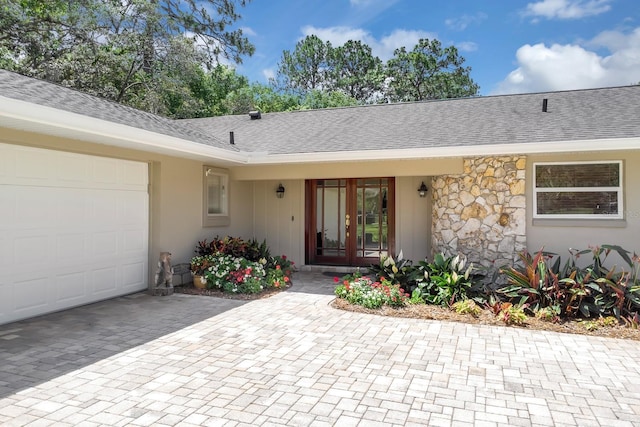 303 S Sweetwater Blvd, Longwood, FL 32779 - view of exterior entry featuring french doors, a garage, roof with shingles, decorative driveway, and stone siding