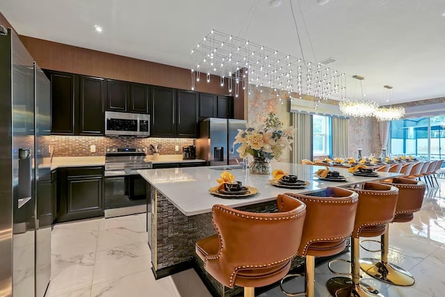 4441 Ganesha Loop, Kissimmee, FL 34746 - kitchen with stainless steel appliances, light marble finish flooring, dark cabinets, tasteful backsplash, and a chandelier