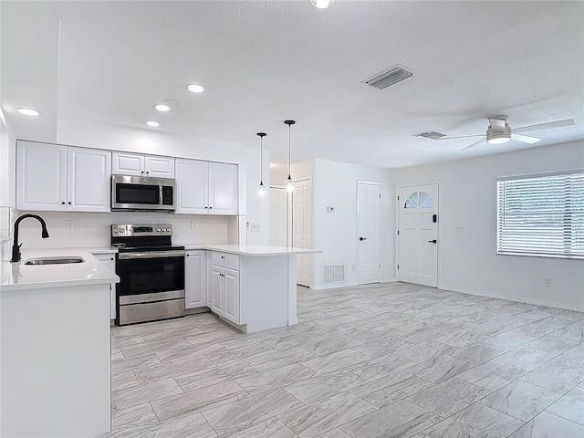 1113 Leeward Dr, Deltona, FL 32738 - kitchen with stainless steel appliances, a sink, a peninsula, light countertops, and white cabinets