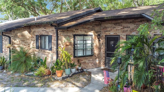 1803 Foxhall Cir Unit 1803, Kissimmee, FL 34741 - doorway to property with brick siding, roof with shingles, and a patio